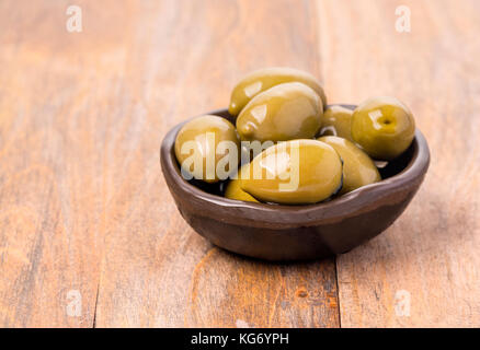 Giant olive verdi in vaso di olive su uno sfondo di legno, fuoco poco profonda Foto Stock