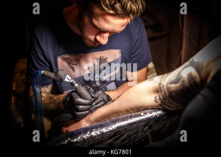 Professional tattoo artist in opera in un tattoo studio. Foto Stock