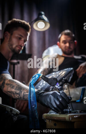 Master tattoo artist prepara gli strumenti per tatuaggio Foto Stock