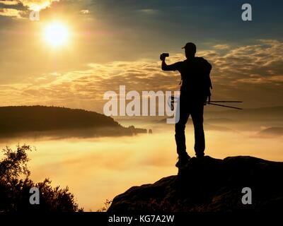 Uomo forte escursionista photogrphy con smart phone al picco di montagna. splendida alba. Foto Stock