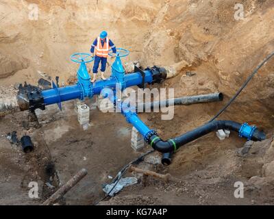 Esperto tecnico metropolitana alla valvola a saracinesca su 500 mm di bere acqua tubi raccordati con nuovo speciale organo di collegamento, nel vecchio sistema di pipeline. Foto Stock