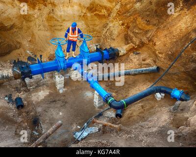 Esperto tecnico metropolitana alla valvola a saracinesca su 500 mm di bere acqua tubi raccordati con nuova eccentrica nera flangia di giunzione nel sistema di condutture. Foto Stock