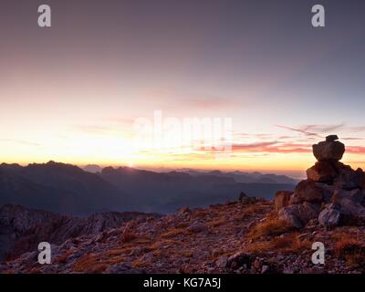 Ciottoli piramide. pietre sulla ghiaia apine mountain summit. alba orizzonte blu sopra la valle di nebbia. montagne aumentata da umidità Foto Stock