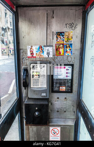 Cabina telefonica sporca che mostra le schede delle scorte incollate all'interno, Londra Centrale, Inghilterra, Regno Unito. Foto Stock