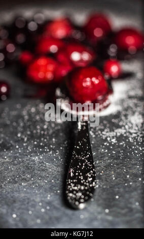 Misto di frutti di bosco selvatici sat su un livello di grigio ardesia piatto di portata spolverati di zucchero con un cucchiaio di lucido Foto Stock