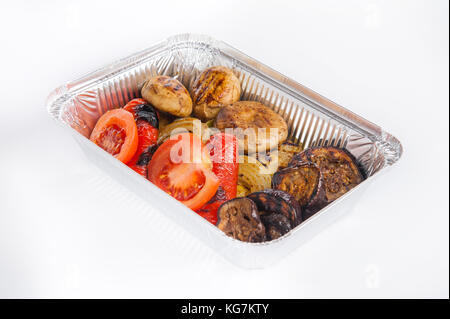 Chiudere fino sano ristorante Consegna del cibo in scatola di lamina. funghi grigliati, la cipolla, i pomodori e le melanzane. I pasti da asporto, il fuoco selettivo. isolato su Foto Stock