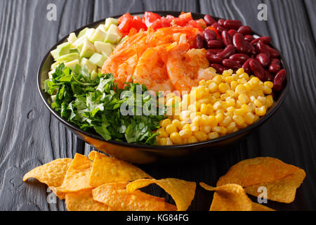 Insalata con gamberi e verdure e nachos vicino sul tavolo orizzontale. Foto Stock