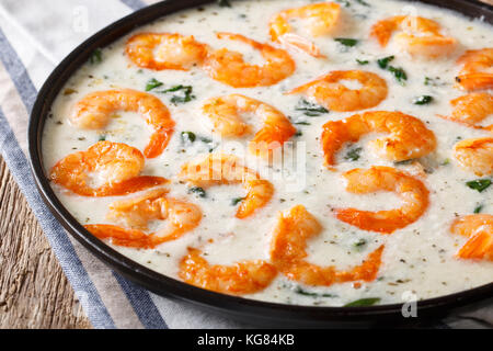 Gamberi deliziosi con spinaci in salsa di formaggio cremosa close-up su una piastra su un piano orizzontale. Foto Stock