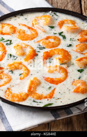 Gamberoni piccanti con spinaci in salsa di formaggio cremosa close-up su una piastra su un piano verticale. Foto Stock