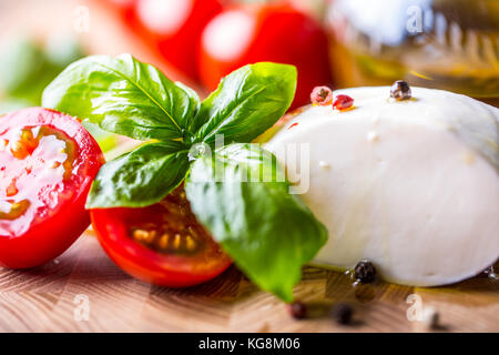 Foglie di basilico, mozzarella di pomodoro e olio d'oliva. Ingredienti su insalata caprese italiana. Foto Stock