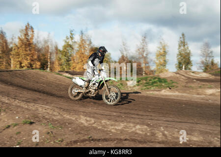 Driver di motocross in azione lo sbarco la moto dopo il salto in pista Foto Stock