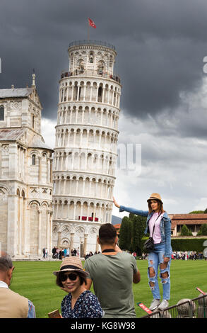 Una giovane e bella donna che pongono apparentemente tenendo premuto fino alla torre pendente di pisa Foto Stock