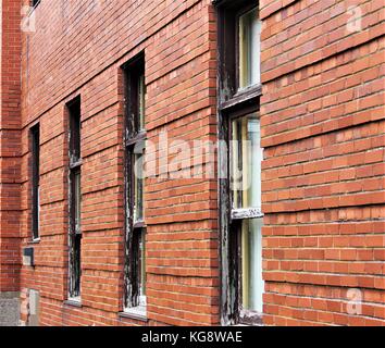 Vecchio legno finestre incorniciate in rosso un muro di mattoni. Foto Stock