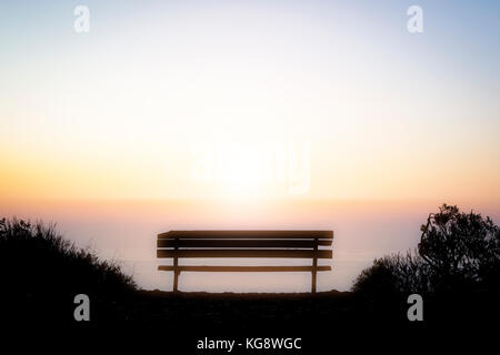 Banco di vuoto che si affaccia la colorata luce del tramonto sopra l'orizzonte dell'oceano pacifico al largo della costa della California Foto Stock