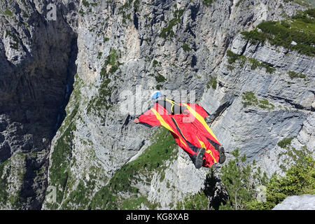 Questo Wingsuit ponticello di base appena scavalcato il ciglio della scogliera e brave diving giù nell'incerto. Ben presto egli deve aprire il suo paracadute da salvare. Foto Stock