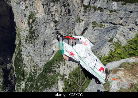 Questo Wingsuit ponticello di base appena scavalcato il ciglio della scogliera e brave diving giù nell'incerto. Ben presto egli deve aprire il suo paracadute da salvare. Foto Stock