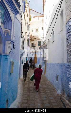 La gente a piedi attraverso il blue-murata di chefchaouen medina, Marocco Foto Stock