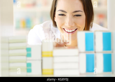 Vista anteriore verticale di un farmacista soddisfatto alla ricerca di medicine in farmacia ripiano Foto Stock