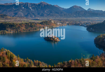 Bled, Slovenia - veduta aerea della chiesa dell'Assunzione di Maria sul Lago di Bled e del Castello di Bled in una soleggiata mattina autunnale con le Alpi Giulie sullo sfondo Foto Stock