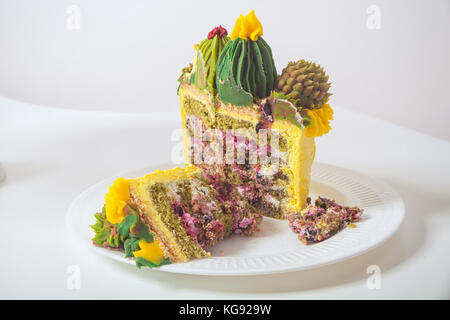 Giallo biscotto torta decorata con una crema di colore verde in forma di fiori e cactus in una cucina luminosa Foto Stock