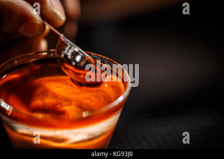 Immagine ravvicinata di barman versa manualmente alcol da misurino in un bicchiere da cocktail Foto Stock