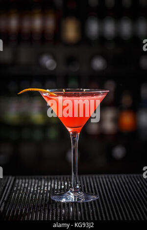 Primo piano di vetro cocktail cosmopolita decorate con la buccia di arancia a sfondo della barra Foto Stock