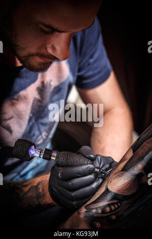 Close up tattoo artist dimostra il processo per ottenere il nero tattoo Foto Stock