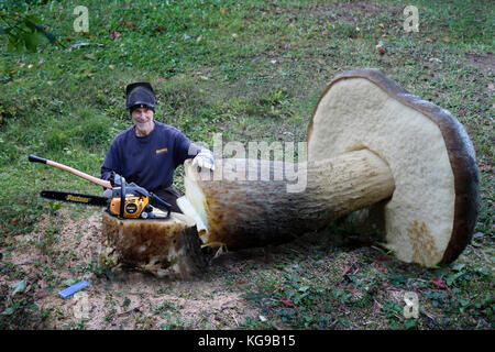 Un sorridente lumberjack con un enorme di funghi commestibili (betulla bolete / Leccinum scabrum) che è stato tagliato con una motosega. (Digitaly manipolato) Foto Stock