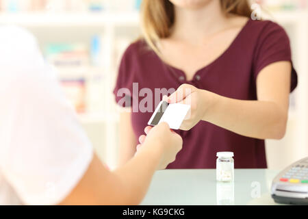 Close up di un cliente dando una carta di credito per il farmacista in una farmacia Foto Stock