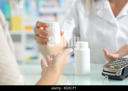 Close up di un farmacista le mani la vendita di farmaci per un cliente su un banco di farmacia Foto Stock