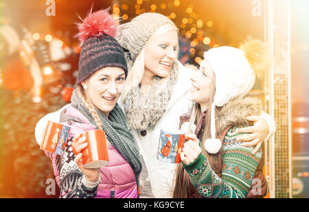 Le donne di bere vino brulé in tazze tedesco sul mercato di natale Foto Stock