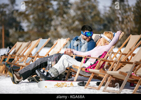 Coppia felice in amore in montagne in inverno a ridere e rilassarsi nel lettino Foto Stock