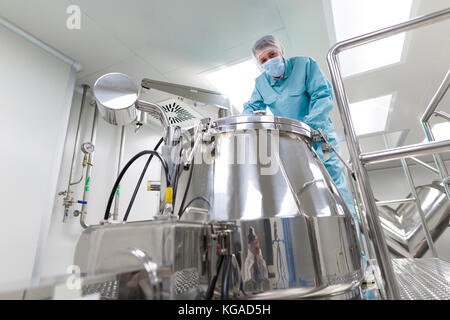 Scienziato guarda in serbatoio di acciaio in laboratorio Foto Stock