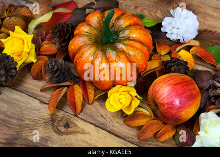 Ringraziamento arancione zucca, Apple, pigne e giallo corona di rose sullo sfondo di legno, close up Foto Stock