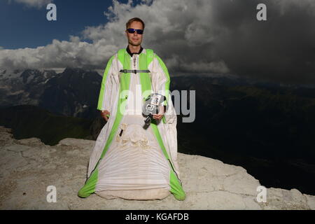 Wingsuit ponticello di base è il pensiero circa il suo passo successivo per passare dalla scogliera dietro di lui. La concentrazione è alta per la successiva fase di lancio verso il basso. Foto Stock