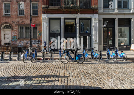 Un ciclista corse citibike passato un parcheggio citibike stand a new york. Foto Stock