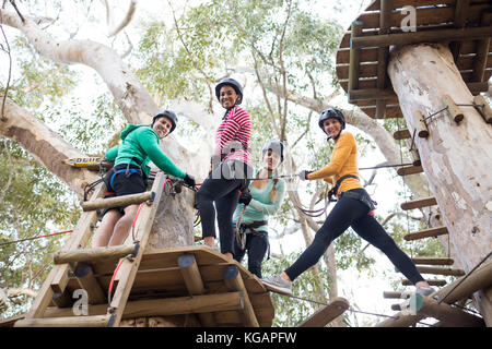 Happy amici ottenere pronto per la zip line a park in una giornata di sole Foto Stock