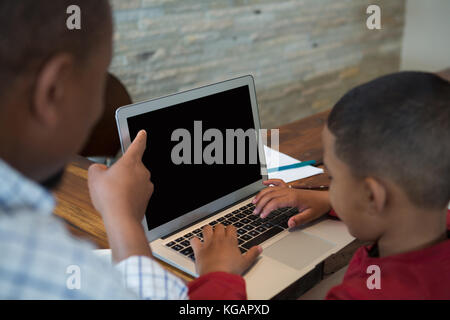 Padre e figlio utilizzando laptop nel salotto di casa Foto Stock