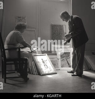 Degli anni Cinquanta, foto storiche che mostra un uomo e una donna di decidere quali immagini per selezionare una galleria display. Foto Stock