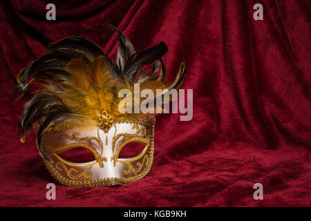 Brown golden carnevale veneziano maschera visto dalla parte anteriore su un drappo di velluto rosso teatro tenda Foto Stock