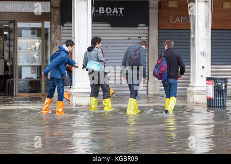 Venezia, Veneto, Italia. 6 Nov, 2017. Acqua Alta alta marea dalla laguna provocando allagamenti temporanei in Piazza San Marco. Un gruppo di quattro persone guadare attraverso l'acqua. Credito: Maria Clarke/Alamy Live News Foto Stock