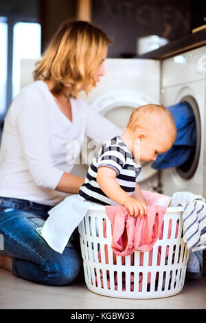 Giovane madre con un bimbo a fare i lavori di casa. Foto Stock
