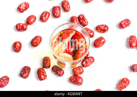 Rosso cinese frutta date di tè in un bicchiere su bianco Foto Stock