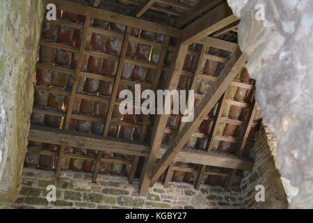 Legname di legno tetto della struttura di dettaglio con mattonelle di terracotta che coprono oltre sostenuti da muri in pietra sulla parte di edificio antico patrimonio nuovamente e la conservazione Foto Stock