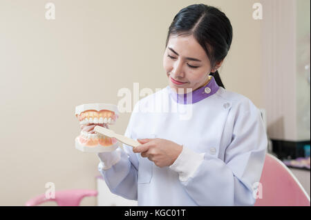 Dentista femmina spiegare circa la spazzolatura dei denti nella clinica di cura per la salute e la manutenzione con il concetto di esperti Foto Stock