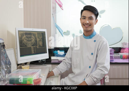 Dentista maschio sedersi accanto allo schermo del computer mentre spiegare circa la somministrazione orale e dei denti problema. per le cure dentarie e manutenzion sani con il concetto di esperti Foto Stock