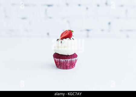 Velluto rosso capcake con crema al mascarpone con Fragola. sfondo bianco. Foto Stock