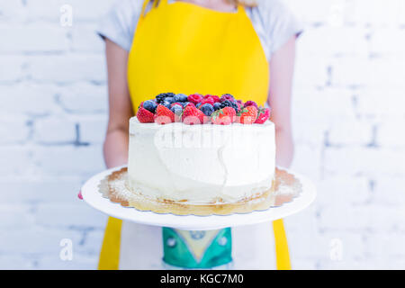 Whoopie pie sulla piastra con frutti di bosco freschi, le mani delle donne azienda. sfondo bianco. Foto Stock