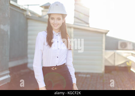 Businesslady attraente in camicia bianca, casco e gonna nera stand sul tetto Foto Stock