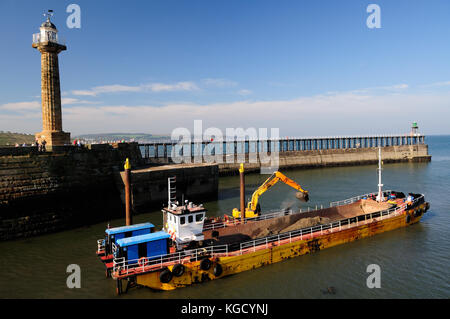 Dragare il canale di navigazione all'ingresso del porto di Whitby. Foto Stock